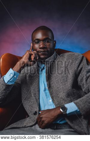 Fashoinable Stylish Blackman Are Sitting On A Chair With Multicolored Background Behind. Business Li