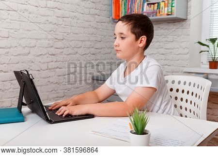 Cheerful Schoolkid Writing In Notebook And Smiling At Camera While Doing Homework. Homeschooling, Di