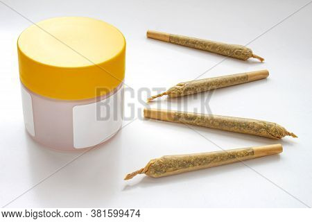A Cannabis White And Yellow Plastic Packaging Container With Cigarettes, Prerolls Or Joints And A On