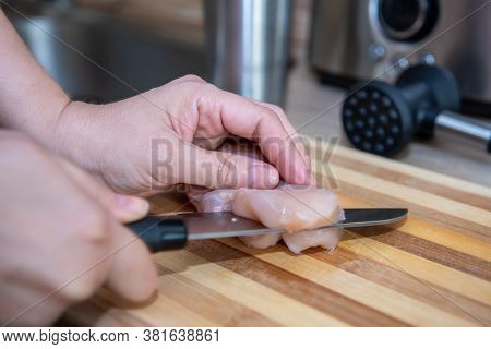 Female Hands Cut Chicken Fillet On Wooden Board With A Knife