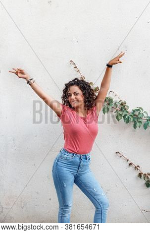 Young Women With Hands Up Stays Near A Wall And Smile