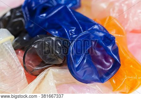 Different Colored Condoms Open And Without Packaging