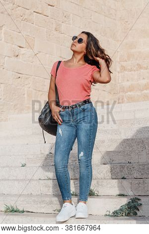 Young Women Wearing T-shirt And Jeans Going Down The  Stairs