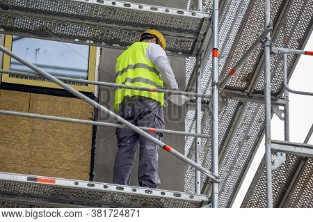 Plastering The Wall Outdoor On Scaffold At Building Under Construction.