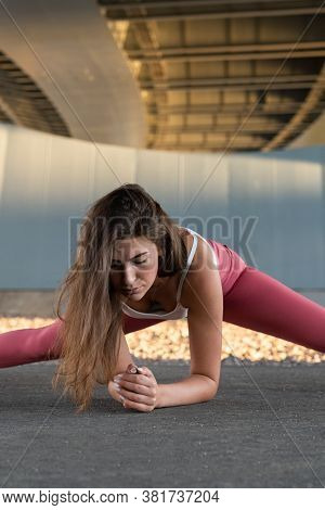 Gymnast Woman In Pink Leggings Doing A Side Split And Stretches For Legs, Practicing Pilates Under T