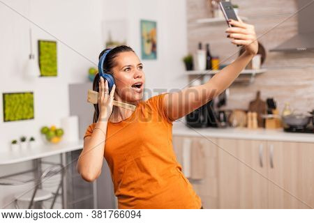 Young Woman Feeling Good In The Morning, Taking A Selfie In The Kitchen And Singing On Wooden Spoon.