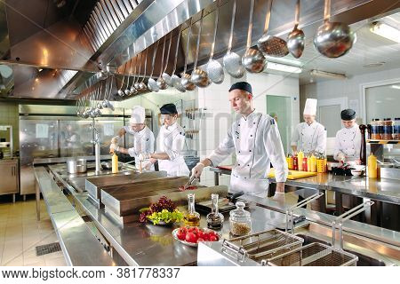 Modern Kitchen. Cooks Prepare Meals On The Stove In The Kitchen Of The Restaurant Or Hotel. The Fire