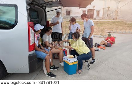 A Large Family With Seven Children Happy To Have A Holiday, Stopping With The Van To Make And Eat So