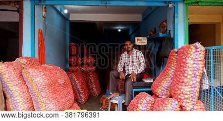 District Katni, India - August 07, 2019: Asian Village Male Store Keeper Sitting In Onion Stocks Pla