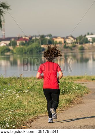 Young Girl Jogging In The Morning. Woman Working Out On Lacul Morii Or Windmill Lake In Bucharest.
