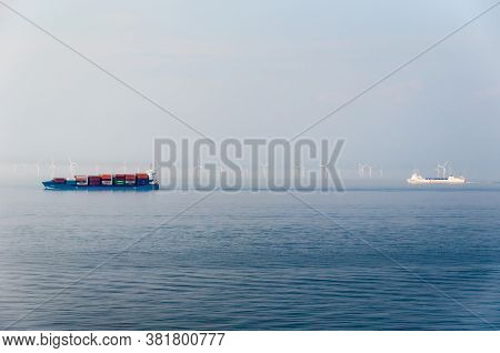 Kiel, Germany - May 11, 2011: Container Ships Are Passing A Large Offshore Windpark During Morning M