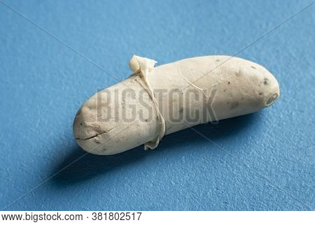 White Sausage Close-up With The Skin Peeled Off, Isolated On A Blue Background. Bavarian Veal Sausag