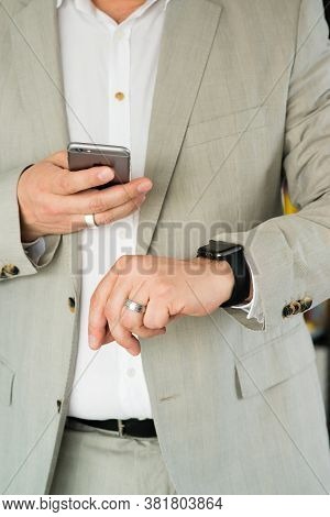 Ostfildern, Germany - May 14, 2015: A Businessman Is Checking His Apple Watch While Using His Iphone