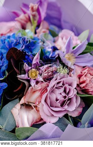 Close-up Bouquet Of Flowers, Packed In Purple Paper On A Light Background. Bouquet Of Eucalyptus, Ca