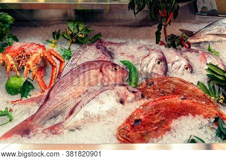 Raw fish and crab on supermarket display, food store, toned