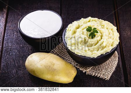 Mashed Potatoes Or Cream Served In A Handmade Clay Pot, With Sour Cream In The Background On A Rusti