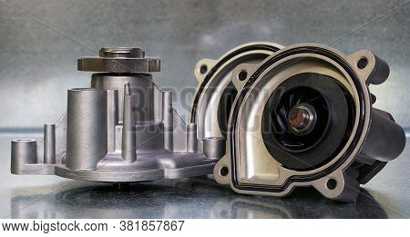 Coolant Pump Of A Modern Car On A Steel Background. Shown From The Outside And From The Impeller Sid