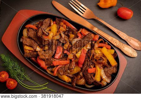 Image Of Fajitos On A Cast Iron Frying Pan On A Wooden Stand With Vintage Cutlery And Vegetables As 