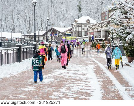 Sochi, Russia - 25 February 2020. Snowboarders And Skiers With Equipment Are Walking Along The Sidew