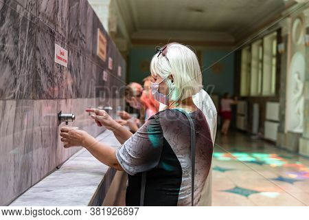 Tourists Of Retirement Age Drink Mineral Water In The Open Narzannaya Gallery In Protective Masks