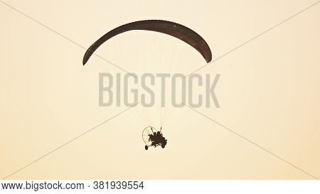 Silhouette Of The Paramotor Tandem Gliding And Flying In The Air. Copy Space High Quality Photo