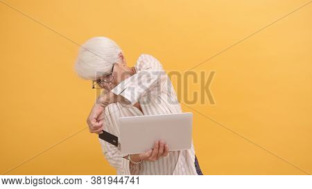 Puzzled Senior Woman Trying To Insert Credit Card In The Laptop. Online Shopping . High Quality Phot