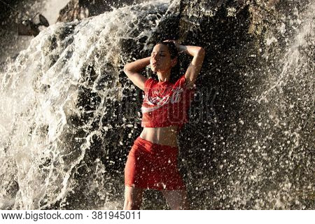 Dnipro. Ukraine -08.14.2019. Woman In Red Shirt And Top Stands Under Waterwall Jets.