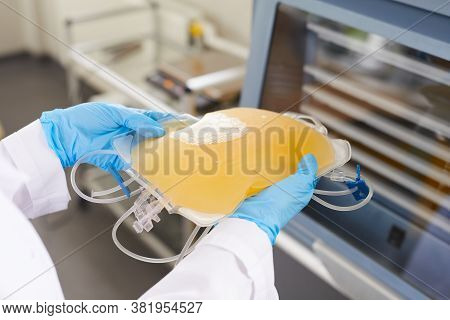 Close-up Of Doctor In Protective Gloves Holding Package With Blood Plazma At Hospital