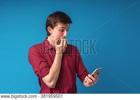 Scared Young Guy Holding A Smartphone In His Hand Covers His Mouth With His Hands In Shock At The Er