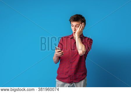 Scared Young Guy Holding A Smartphone In His Hand Covers His Face With His Hand In Shock At The Erro