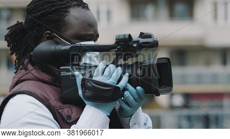 Close Up, African Black Videographer With Medikal Mask Looking Through The Viewfinder On Video Camer