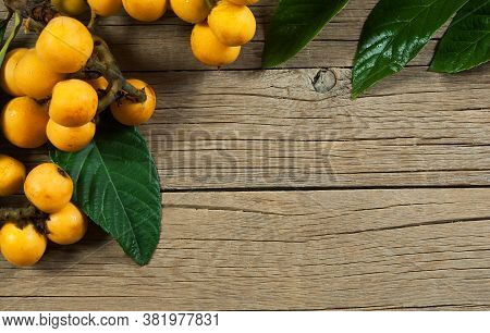 Fresh Ripe Loquat Japanese Medlar Fruit With Branch And Leaf On Wooden Background, Malta Plum, Summe