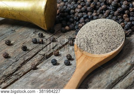 Heap Of Black Pepper And Black Pepper Powder In Wooden Spoon, Milled Peppercorns On Wooden Backgroun