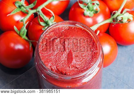 Tomato Paste In Wooden Spoon And Ripe Fresh Grape Tomatoes On Wooden Background. Cherry Tomatoes. To