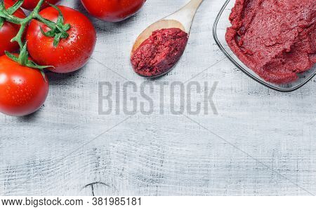 Tomato Paste In Wooden Spoon And Ripe Fresh Grape Tomatoes On Wooden Background. Cherry Tomatoes. To