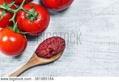 Tomato Paste In Wooden Spoon And Ripe Fresh Grape Tomatoes On Wooden Background. Cherry Tomatoes. To