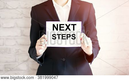 Woman Showing White Card With Next Steps Word . Business Concept