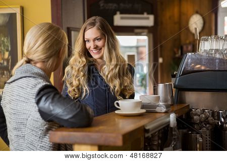 Felice femminili amici conversando dal contatore in coffeeshop