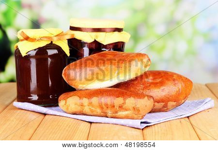 Empanadillas al horno frescos con mermelada de frutas, en la mesa de madera, sobre fondo brillante