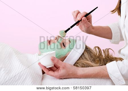 Beautician Brushing Green Facial Mask On A Woman.
