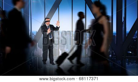 Mature businessman in a blindfold against room with large window looking on city