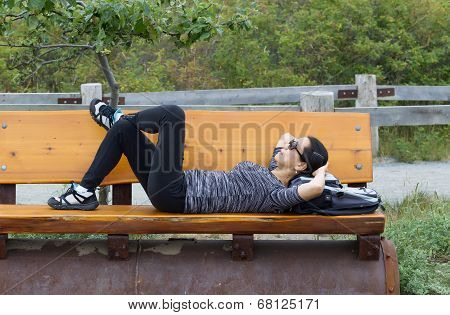 Mature Woman Hiker Taking A Break On Wooden Bench