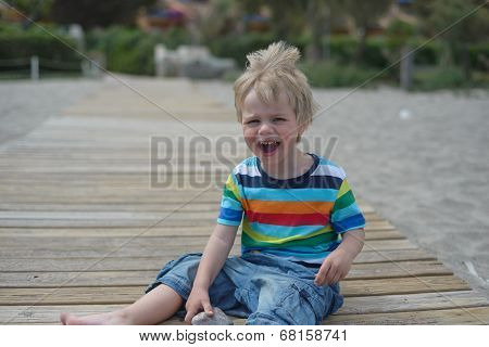 Flashy boy sits on a wooden walkway on the beach
