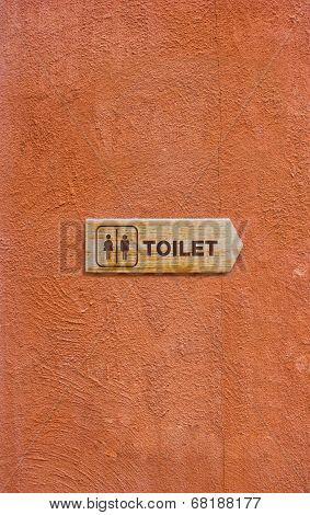 Wooden Toilet Sign On The Orange Wall.