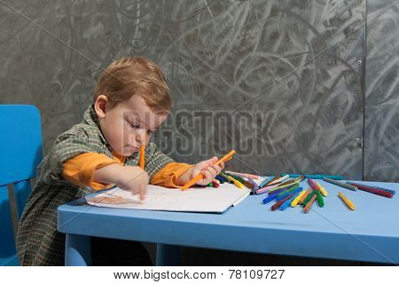 Child Sitting At A Table Drawing With Colored Markers