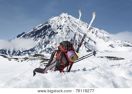 Backpack, Skis And Poles Lie On The Snow On Background Volcano