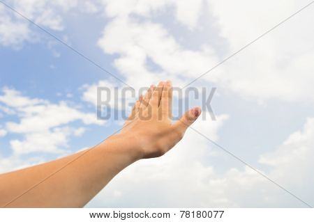 Hand palm on the blue sky with clouds