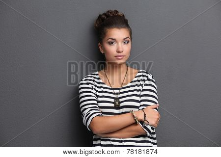 A young woman standing, isolated on graybackground.