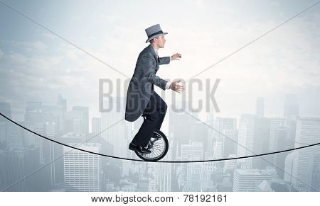 Brave guy riding a monocycle on a rope above cityscape concept