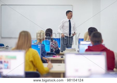 group of students with teacher in computer lab classrom learrning lessons,  get help and support